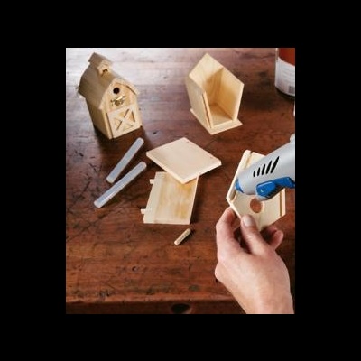 Peças de madeira para uma casinha de pássaros sobre mesa com cola quente e bastões de cola