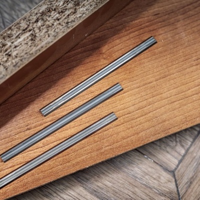 Três ralos metálicos lineares sobre tábuas de madeira.