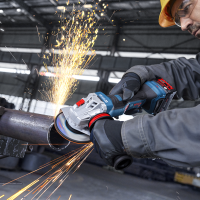 Máquina angular Bosch a cortar tubo metálico com faíscas em ambiente industrial