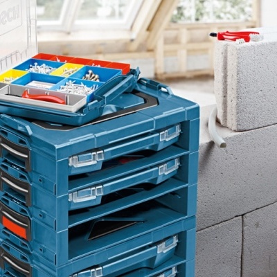 Caixas organizadoras azuis empilhadas com compartimentos coloridos num ambiente de construção