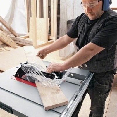 Homem a cortar madeira com serra circular elétrica numa oficina de carpintaria