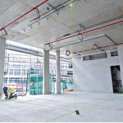 Interior de construção com trabalhador, pilares, paredes brancas e feixes de laser verdes