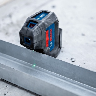 Nível laser Bosch azul e preto com laser verde num chão cinzento