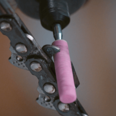 Ferramenta com corrente metálica e broca com peça rosa num suporte preto