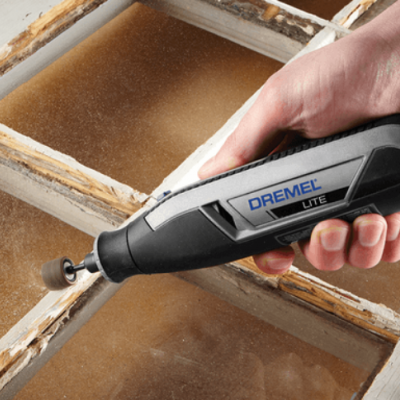 Ferramenta rotativa Dremel Lite a lixar madeira envelhecida de uma moldura de janela