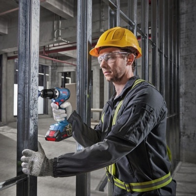 Trabalhador com capacete e furadeira elétrica em obra