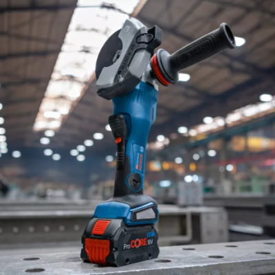 Esmerilhadora portátil azul e preta com bateria vermelha numa bancada metálica em ambiente industrial