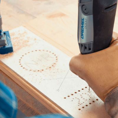 Ferramenta rotativa Dremel a trabalhar madeira com furos e marcas circulares
