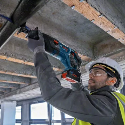 Trabalhador em colete refletor usando ferramenta elétrica Bosch num teto de cimento