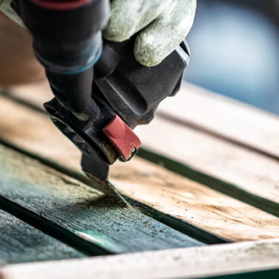 Broca elétrica a trabalhar em madeira com punho preto e vermelho