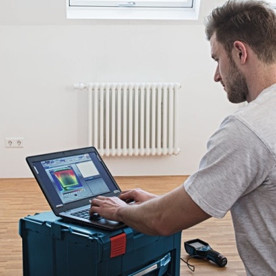 Homem a usar portátil numa mala azul em sala clara