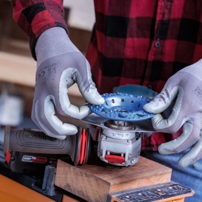 Pessoa segurando esmerilhador azul e cinza com luvas cinza