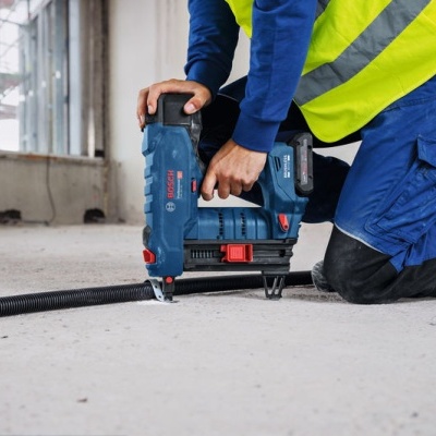 Pessoa a usar pistola de pregos Bosch Direct azul e preto em obra