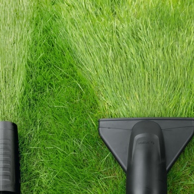 Ferramentas de aspiração pretas limpando relva verde