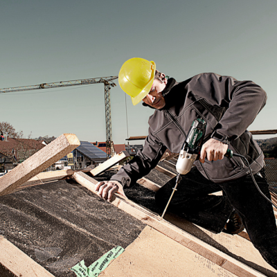 Homem a trabalhar numa cobertura com capacete amarelo e ferramentas