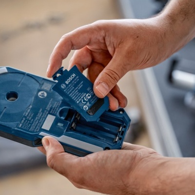 Mãos a colocar bateria Bosch num carregador azul