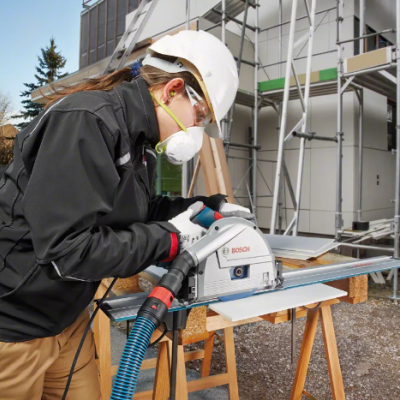 Mulher a usar serra circular Bosch GKS 65 para cortar madeira num local de construção