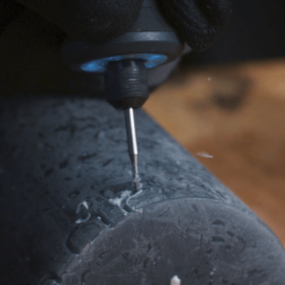 Ferramenta elétrica com broca fina a trabalhar em objeto cilíndrico preto