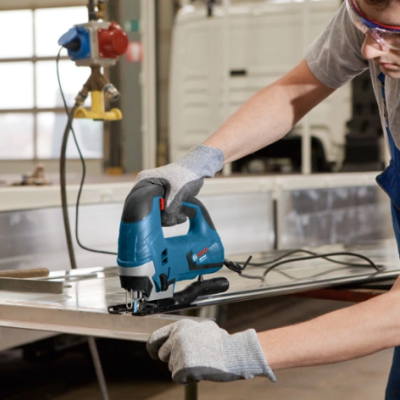 Pessoa a cortar metal com serra tico-tico numa oficina