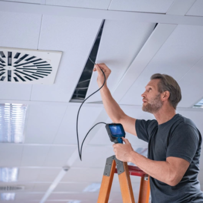Homem a inspecionar teto falso com câmara de inspeção