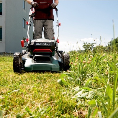 Corta-relva Metabo verde a cortar relva num jardim