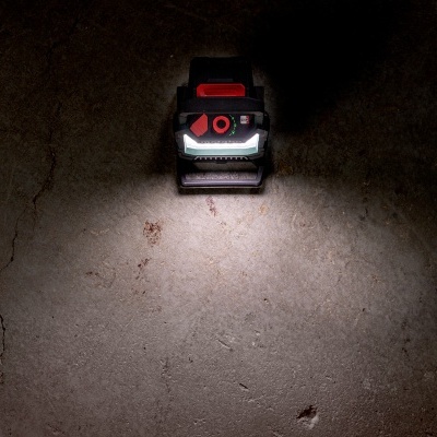 Lanterna preta com luz branca sobre chão de cimento