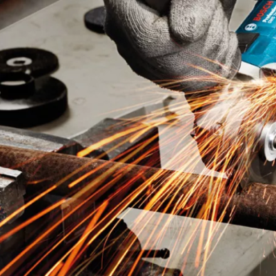 Pessoa a cortar tubo de metal enferrujado com rebarbadora azul