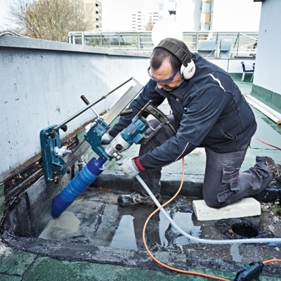 Trabalhador a usar máquina de perfuração Bosch num espaço exterior urbano