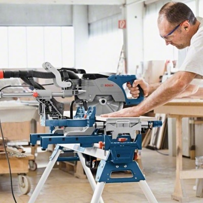 Serra de esquadria Bosch azul e cinzenta em oficina de madeira.