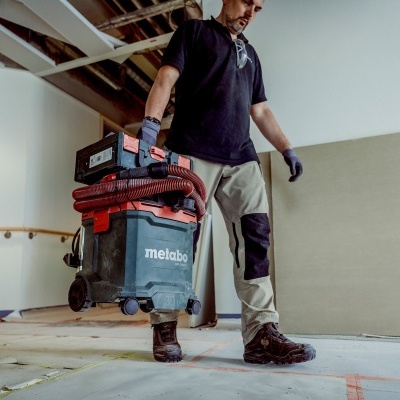 Aspirador industrial Metabo preto e vermelho num interior em construção