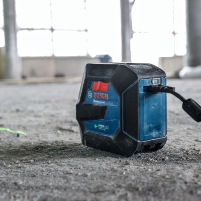 Laser de nível BOSCH azul e preto no chão de cimento num ambiente industrial