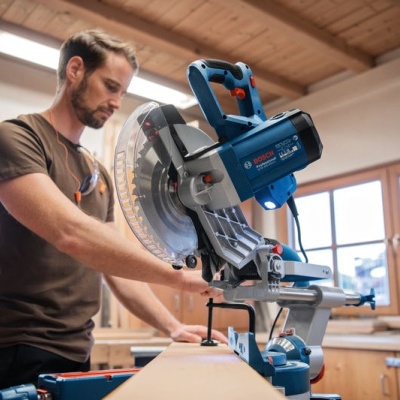 Serra de esquadria elétrica Bosch azul e cinza numa oficina com homem a usar