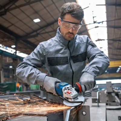 Homem a usar rebarbadora num ambiente industrial