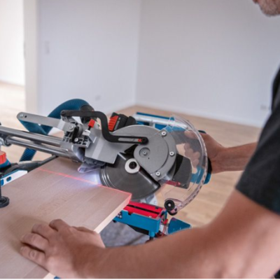 Máquina de cortar madeira com lâmina circular e proteções transparentes em uso por pessoa