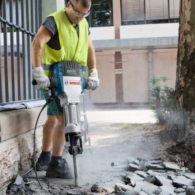 Homem a usar martelo pneumático Bosch para quebrar pedra exterior