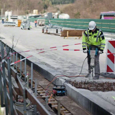 Trabalhador em estrada em construção com máquina azul e fita vermelha e branca