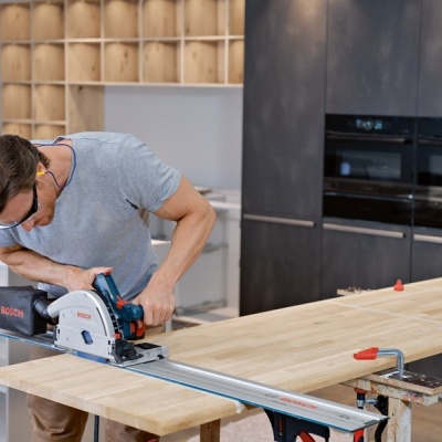 Homem a cortar madeira com serra circular Bosch numa oficina
