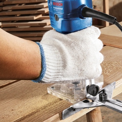 Lixadeira elétrica Bosch Professional azul em uso sobre madeira com mão enluvada.