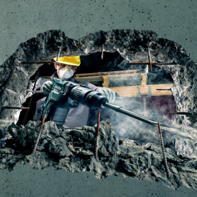 Homem com máscara e viseira operando equipamento em buraco na parede de concreto