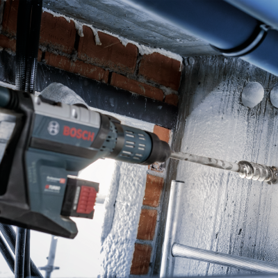 Martelo perfurador elétrico Bosch a perfurar parede de betão com tubos visíveis