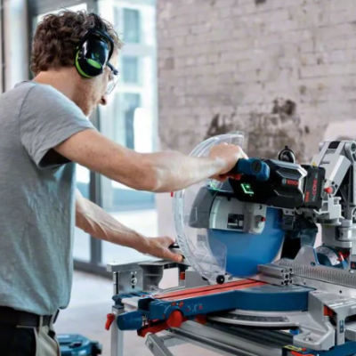 Máquina de cortar esquadrias portátil azul e cinzenta com homem a operar em ambiente industrial