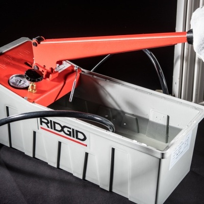 Bomba manual vermelha numa caixa cinzenta com logotipo RIDGID