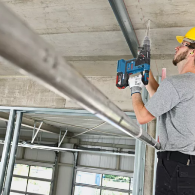 Homem com capacete a usar furadeira elétrica num teto de betão