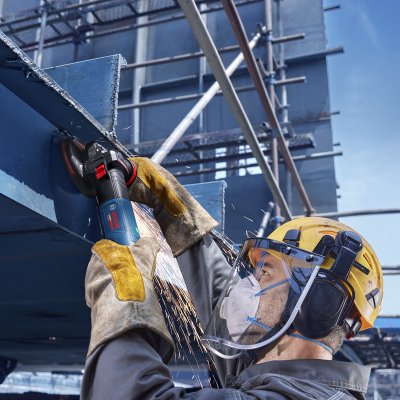 Trabalhador com capacete e proteção a usar esmerilhadora Bosch numa obra