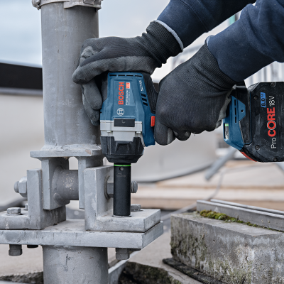 Parafusadeira Bosch sem fios a apertar parafuso em suporte metálico cinza ao ar livre