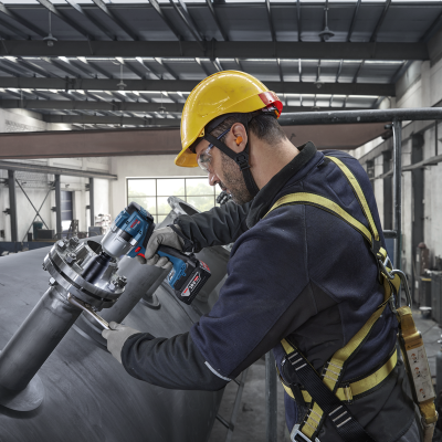 Trabalhador com capacete amarelo e ferramenta elétrica Bosch a operar em estrutura metálica
