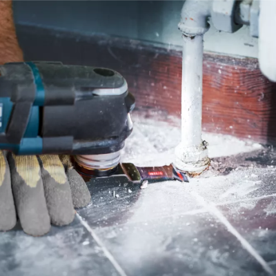 Ferramenta elétrica a trabalhar num piso com canos próximo
