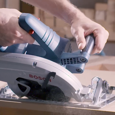Serra circular elétrica Bosch cinza a cortar madeira numa bancada
