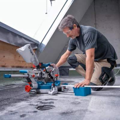 Homem usando serra de esquadria ao ar livre numa superfície de betão