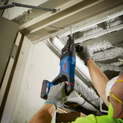 Pessoa a usar ferramenta elétrica Bosch para perfurar teto em construção